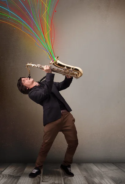 Aantrekkelijke musicus spelen op saxofoon terwijl kleurrijke abstract — Stockfoto