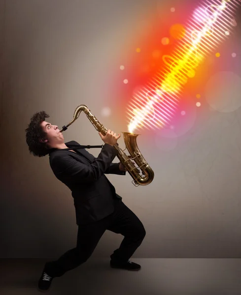 Young man playing on saxophone with colorful sound waves — Stock Photo, Image