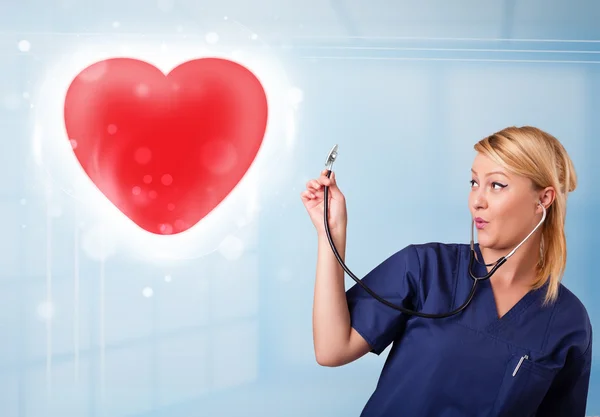 Enfermera joven curando un corazón rojo —  Fotos de Stock