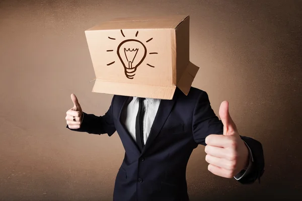 Бизнесмен жестикулирует с картонной коробкой на голове со светом — стоковое фото