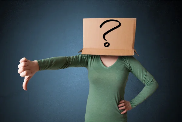 Young lady gesturing with a cardboard box on her head with quest — Stock Photo, Image