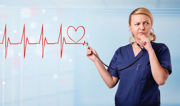 Young nurse listening to abstract pulse with red heart — Stock Photo, Image