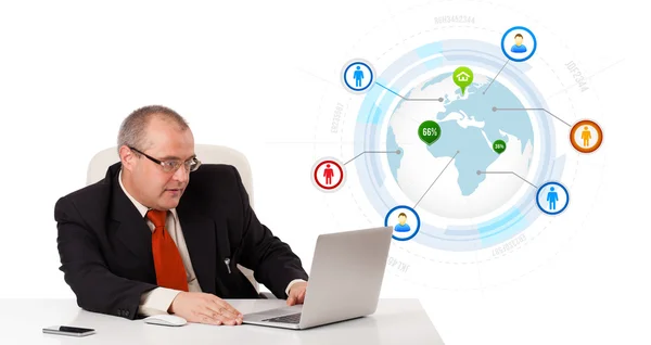 Businessman sitting at desk and looking laptop with globe and so Stock Photo