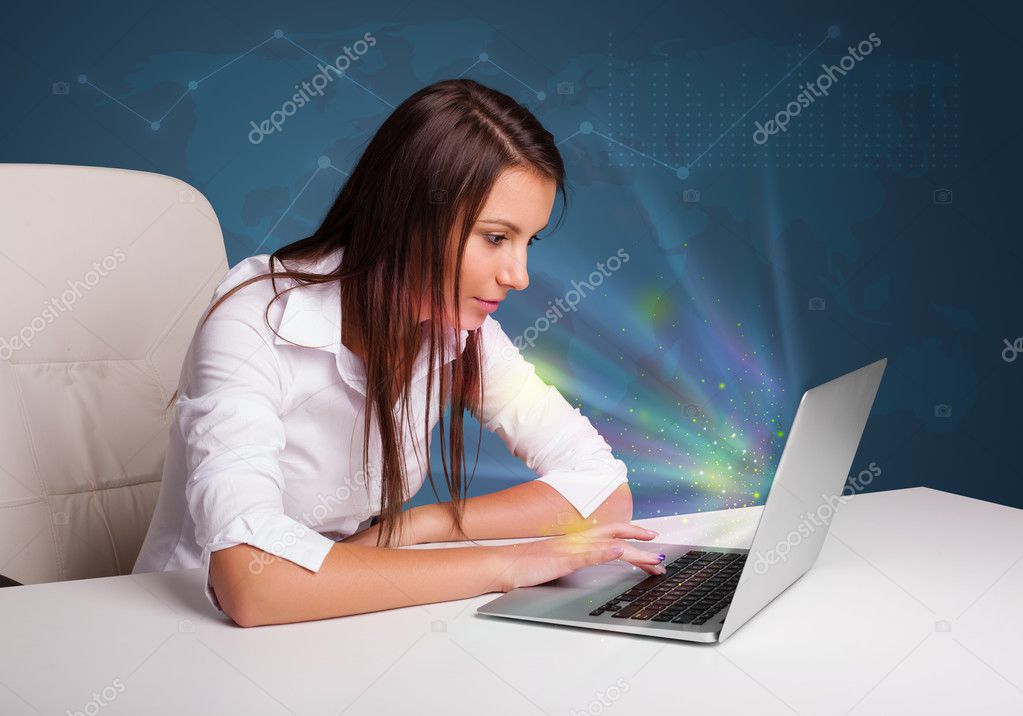Beautiful woman sitting at desk and typing on laptop with abstra
