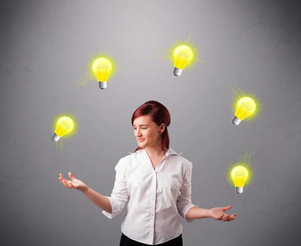 Young lady standing and juggling with light bulbs — Stock Photo, Image