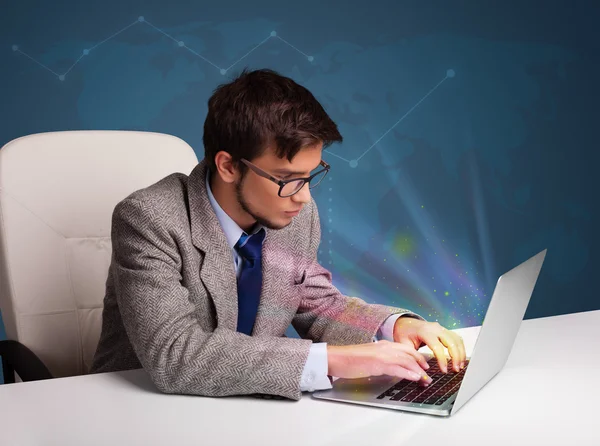 Hombre guapo sentado en el escritorio y escribiendo en el ordenador portátil con abstracto — Foto de Stock