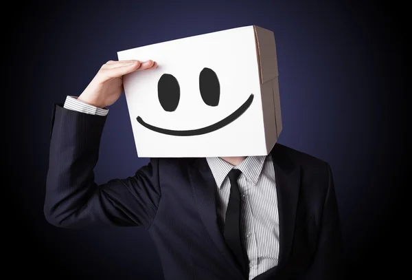 Empresário gesticulando com uma caixa de papelão na cabeça com smil — Fotografia de Stock