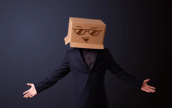 Joven haciendo un gesto con una caja de cartón en la cabeza con sonriente — Foto de Stock