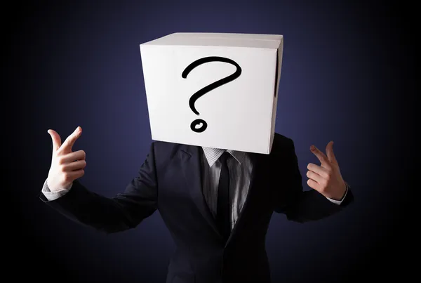 Empresario haciendo gestos con una caja de cartón en la cabeza con preguntas —  Fotos de Stock