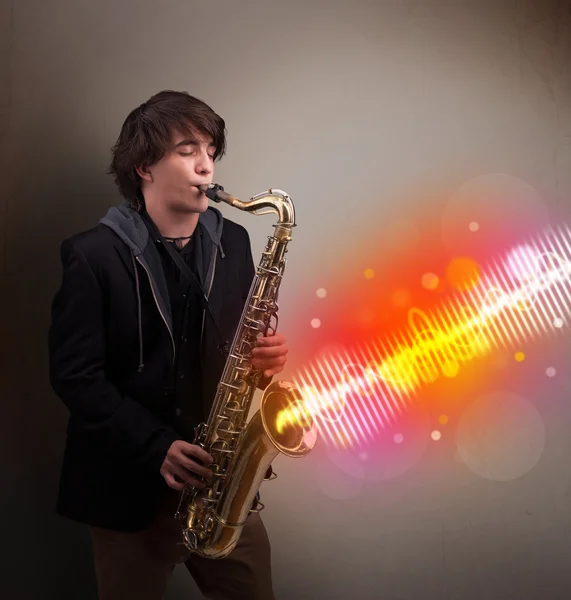 Young man playing on saxophone with colorful sound waves — Stock Photo, Image