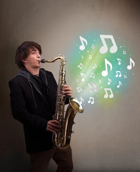 Joven músico tocando el saxofón mientras las notas musicales explotan — Foto de Stock