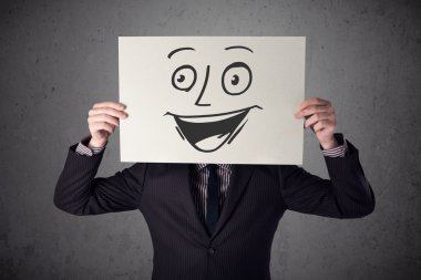 empresario sosteniendo una cartulina con cara sonriente en él en frente