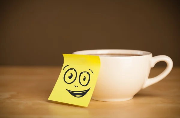 Nota post-it con la cara sonriente pegada en la taza — Foto de Stock