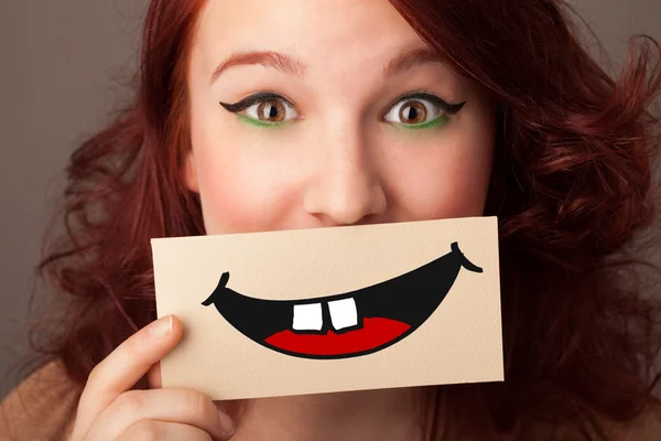 Happy pretty woman holding card with funny smiley — Stock Photo, Image