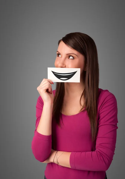 Happy pretty woman holding card with funny smiley — Stock Photo, Image