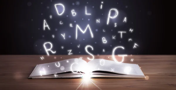 Open book with glowing letters flying out — Stock Photo, Image