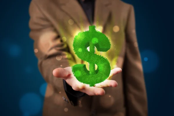 Young businessman presenting green glowing dollar sign — Stock Photo, Image