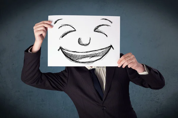 Empresário segurando um papel com rosto sorridente na frente de sua hea — Fotografia de Stock