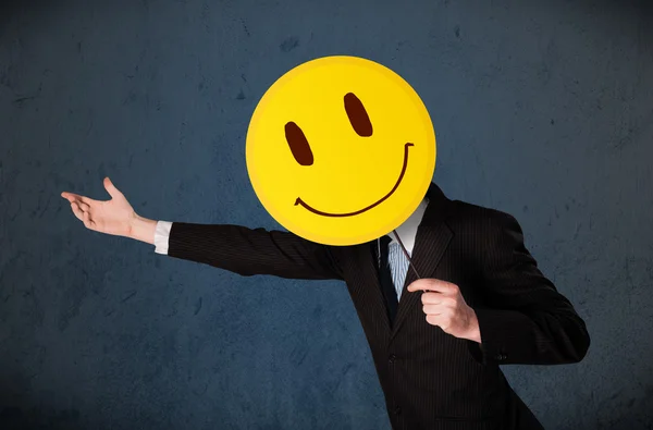 Biznesmen trzymający emotikonę uśmiechniętej twarzy — Zdjęcie stockowe