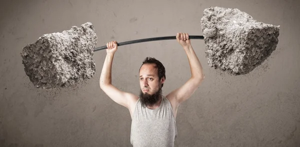 Skinny guy lifting large rock stone weights — Stock Photo, Image