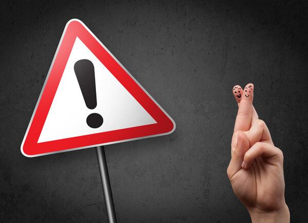Счастливые улыбающиеся пальцы глядя на треугольник предупреждающий знак с excla
