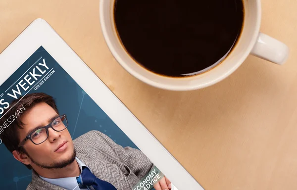 Tablet pc showing magazine on screen with a cup of coffee on a d — Stock Photo, Image