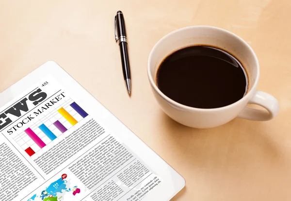 Tablet pc shows news on screen with a cup of coffee on a desk — Stock Photo, Image