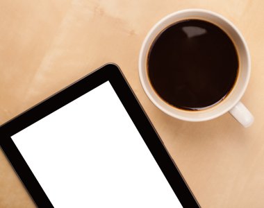 Boş alanı olan bir tablet bilgisayar ve masada bir fincan kahve.