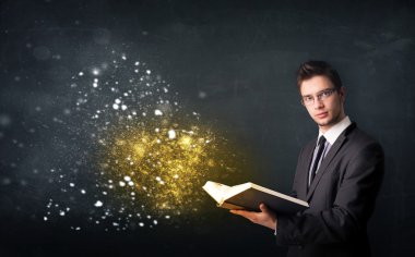 Genç adam sihirli bir kitap okuyor.