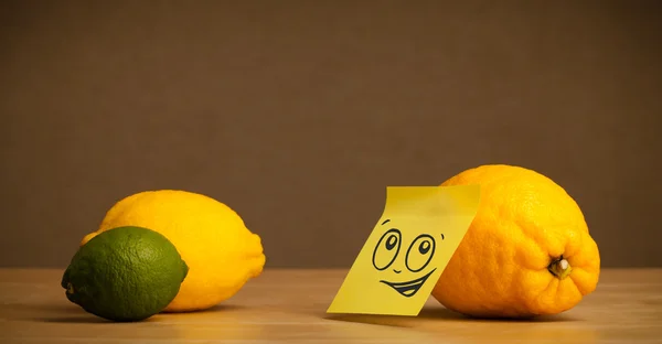 Lemon with post-it note looking at citrus fruits — Stock Photo, Image