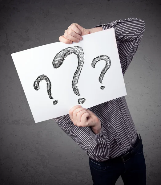 Businessman holding a paper with question marks in front of his — Stock Photo, Image