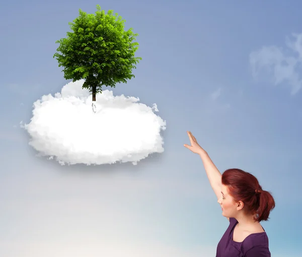 Young girl pointing at a green tree on top of a white cloud — Stock Photo, Image