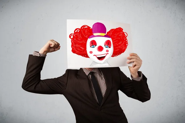 Geschäftsmann hält einen Karton mit einem Clown davor — Stockfoto