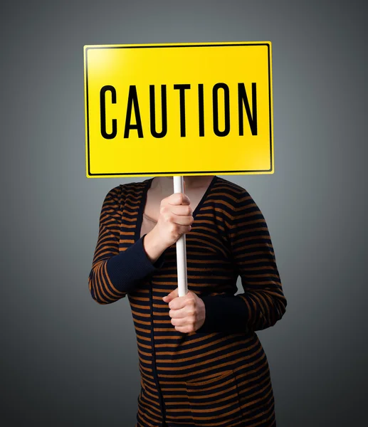 Young woman holding a caution sign — Stock Photo, Image