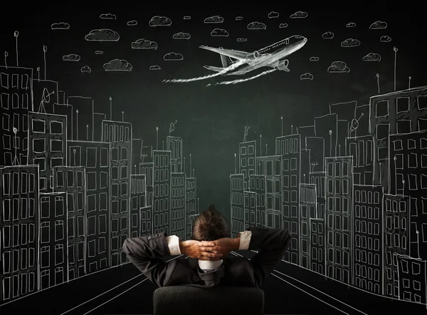 Businessman sitting in front of a cityscape drawing on a chalkbo — Stock Photo, Image