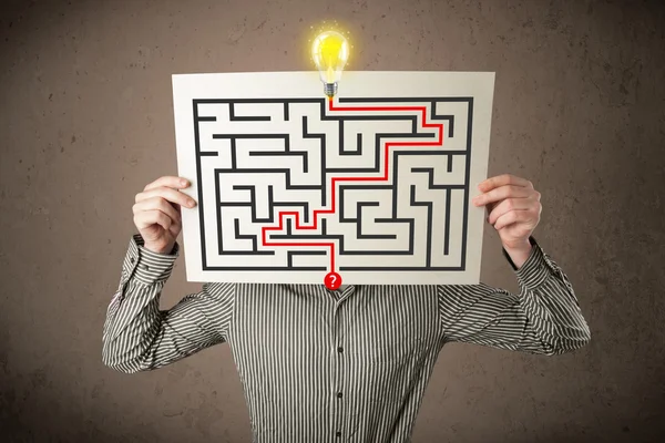 Businessman holding a paper with a labyrinth on it in front of h — Stock Photo, Image