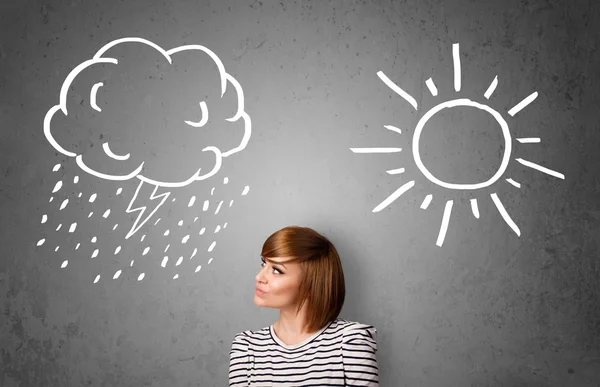 Kvinna som står mellan en sol och en regn ritning — Stockfoto