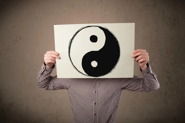 Businessman holding a paper with a yin-yang on it in front of hi — Stock Photo, Image