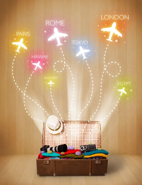 Travel bag with clothes and colorful planes flying out — Stock Photo, Image