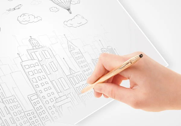 A person drawing sketch of a city with balloons and clouds on a — Stock Photo, Image