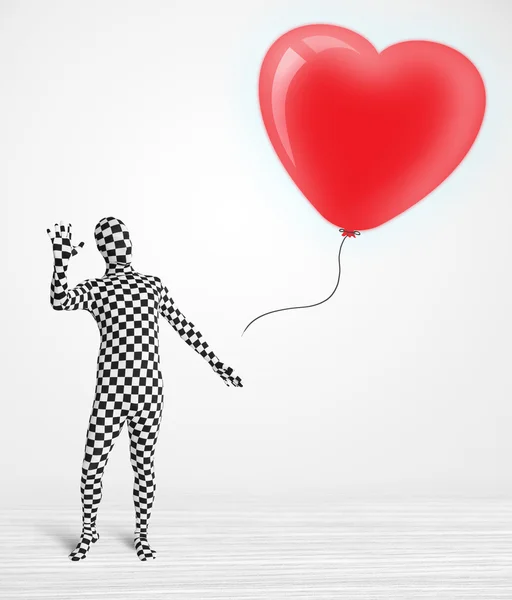 Lindo tipo en traje de cuerpo morpsuit mirando un corazón en forma de globo — Foto de Stock