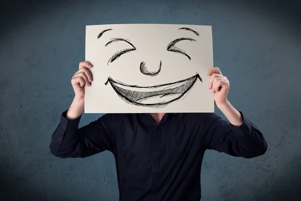 Empresário segurando um papel com rosto sorridente na frente de sua hea — Fotografia de Stock