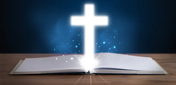 Відкрита священна Біблія з сяючим хрестом посередині — стокове фото