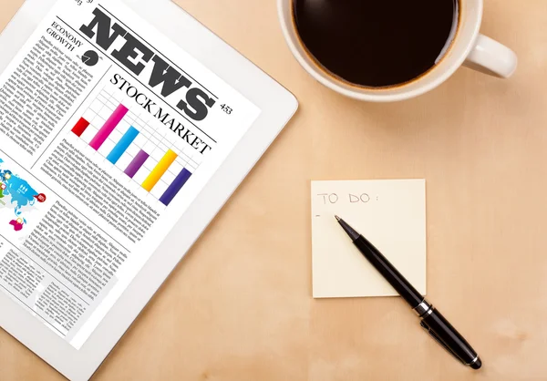 Tablet pc shows news on screen with a cup of coffee on a desk — Stock Photo, Image