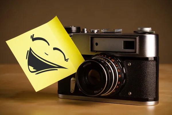 Post-it nota con la cara sonriente pegado en la cámara de fotos — Foto de Stock