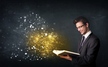 Genç adam sihirli bir kitap okuyor.