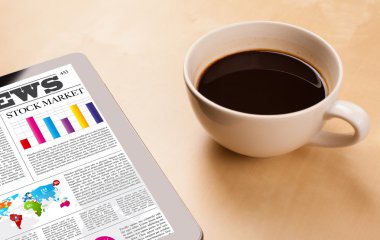 Tablet bilgisayarı haberleri ekranda bir fincan kahveyle sunar.