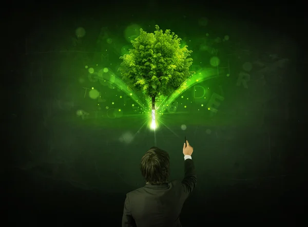 Podnikatel gestikuluje před zářícím stromem — Stock fotografie