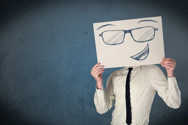 Empresario sosteniendo un papel con la cara sonriente delante de su hea — Foto de Stock