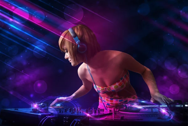 Young DJ playing on turntables with color light effects — Stock Photo, Image